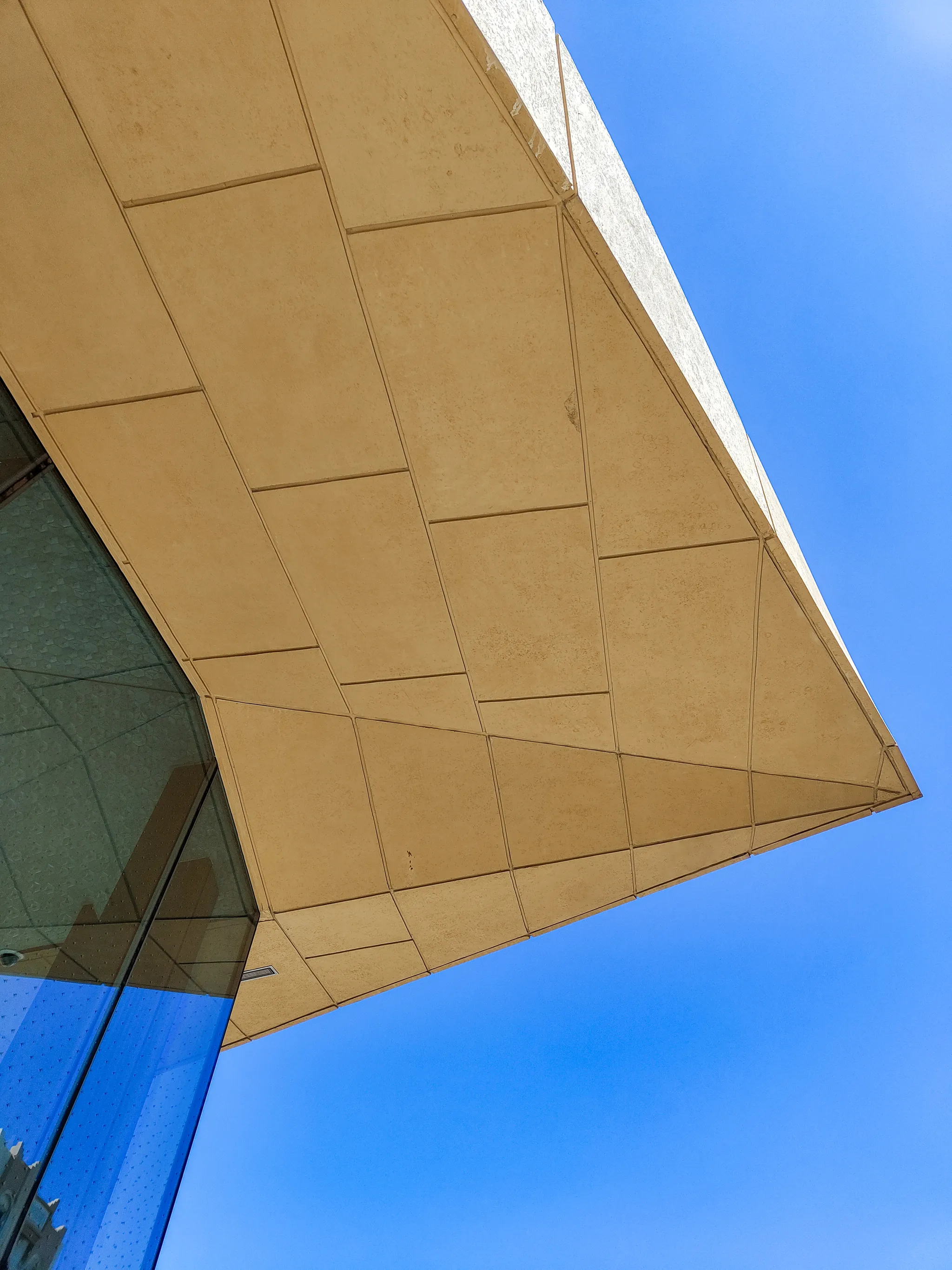 A shot below one of the corners of the metro station, showing the angled roof.