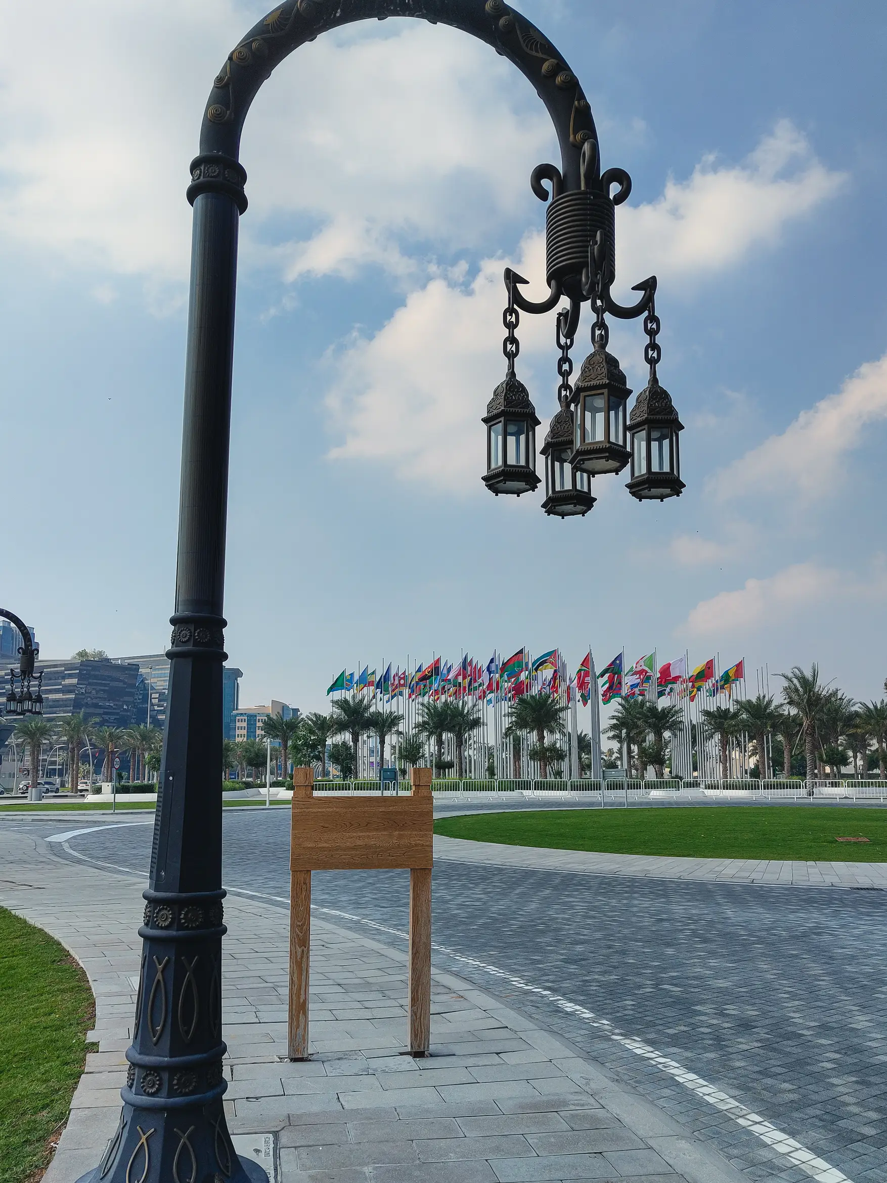 A shot of a vintage street light with 'Flag Plaza' in the background, a collection of almost all major flags.